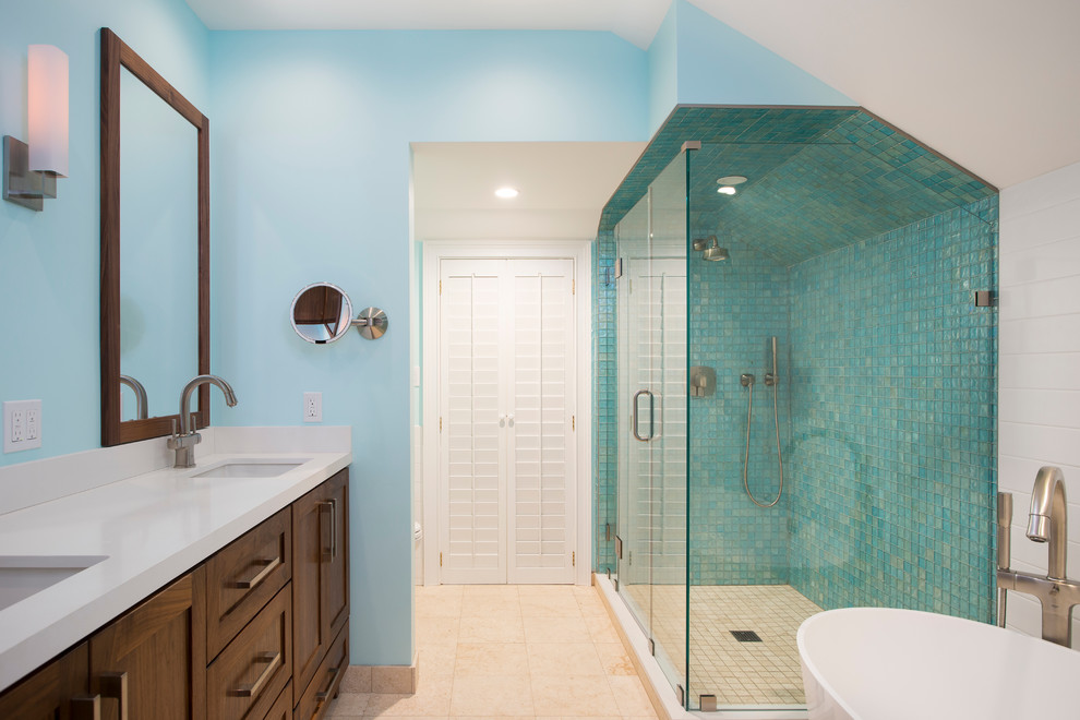Medium sized nautical ensuite bathroom in Miami with shaker cabinets, dark wood cabinets, a freestanding bath, a corner shower, a one-piece toilet, multi-coloured tiles, glass tiles, blue walls, travertine flooring, a submerged sink and engineered stone worktops.