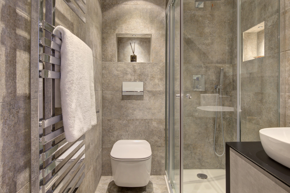 Inspiration för små moderna brunt en-suite badrum, med släta luckor, bruna skåp, en hörndusch, en vägghängd toalettstol, grå kakel, keramikplattor, grå väggar, klinkergolv i porslin, ett fristående handfat, träbänkskiva, grått golv och dusch med skjutdörr