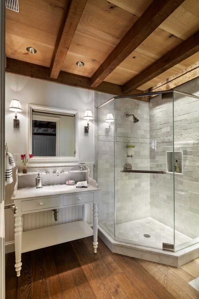 他の地域にある中くらいなエクレクティックスタイルのおしゃれな浴室 (コーナー設置型シャワー、白いタイル、大理石タイル、白い壁、無垢フローリング、コンソール型シンク、茶色い床、開き戸のシャワー) の写真