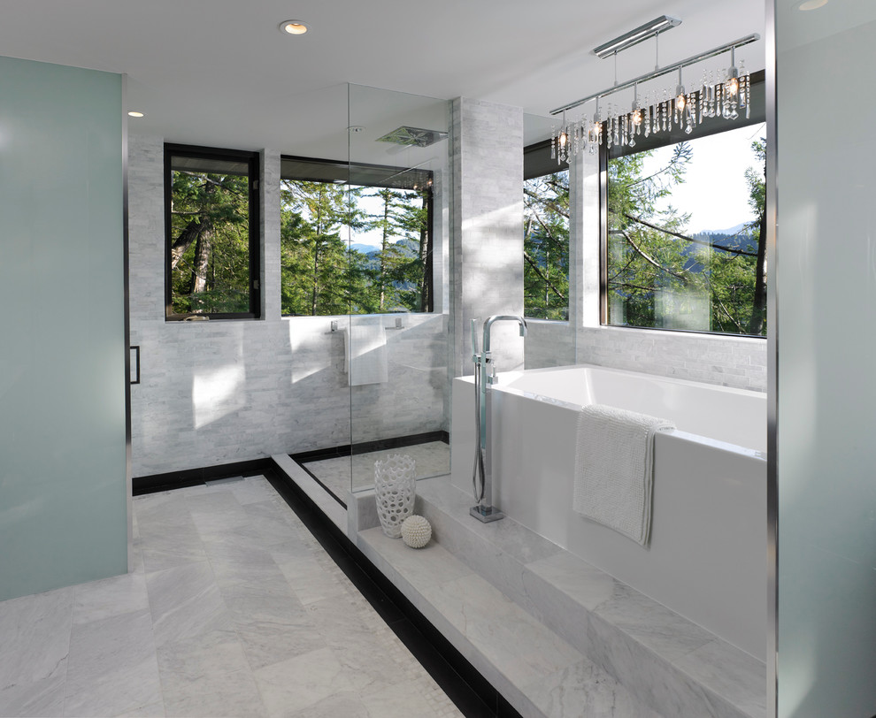 Inredning av ett modernt badrum, med ett fristående badkar, en öppen dusch, grå kakel och med dusch som är öppen