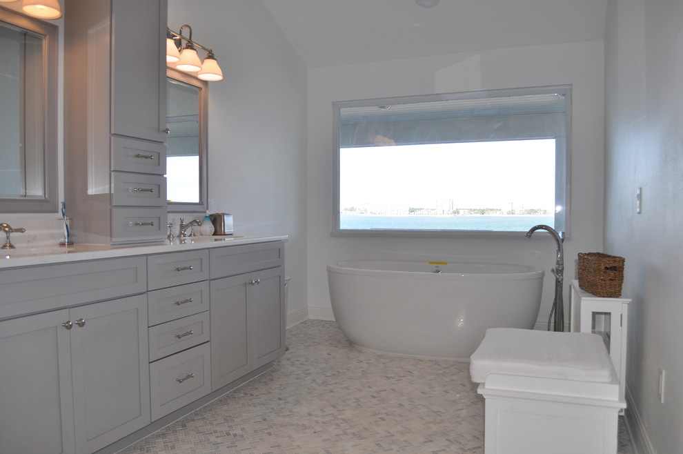 Bild på ett litet maritimt en-suite badrum, med grå skåp, ett fristående badkar, grå kakel, stenkakel, marmorgolv, marmorbänkskiva, luckor med profilerade fronter, en dusch/badkar-kombination, en toalettstol med hel cisternkåpa, vita väggar och ett nedsänkt handfat