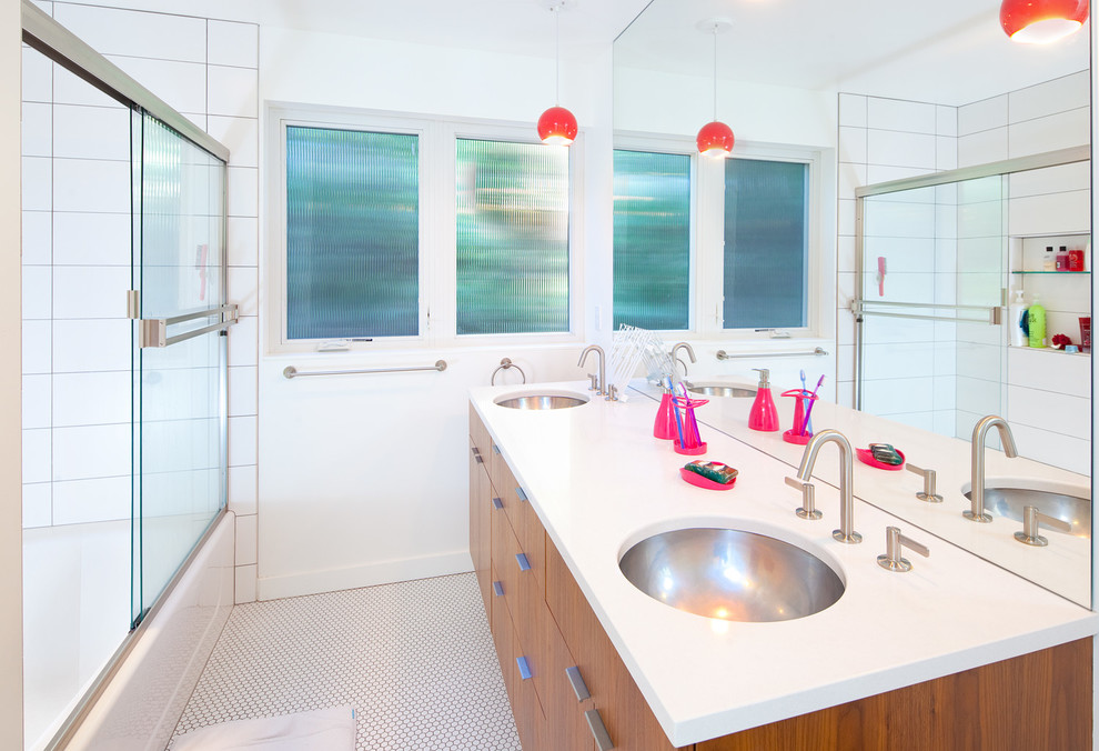 Foto di una stanza da bagno minimalista con lavabo sottopiano, ante lisce, ante in legno scuro, vasca/doccia, piastrelle bianche e pareti bianche