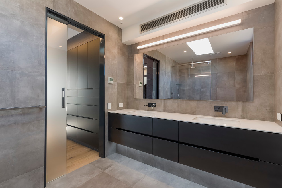 Foto di una grande stanza da bagno padronale minimalista con ante lisce, ante nere, piastrelle grigie, piastrelle in gres porcellanato e top in quarzo composito
