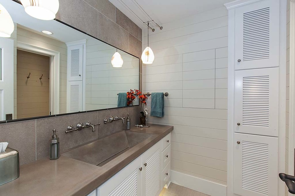 Bild på ett mellanstort maritimt badrum med dusch, med ett avlångt handfat, luckor med lamellpanel, vita skåp, bänkskiva i betong, grå kakel, stenkakel, beige väggar och klinkergolv i keramik