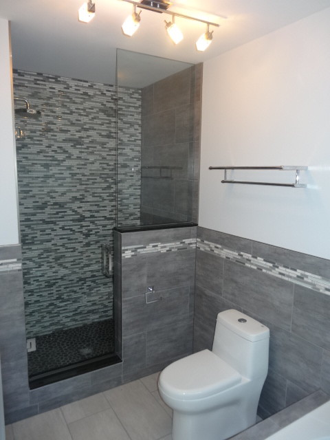 This is an example of a medium sized contemporary ensuite bathroom in Toronto with a vessel sink, a corner bath, an alcove shower, a one-piece toilet, recessed-panel cabinets, dark wood cabinets, solid surface worktops, grey tiles, porcelain tiles, white walls and porcelain flooring.