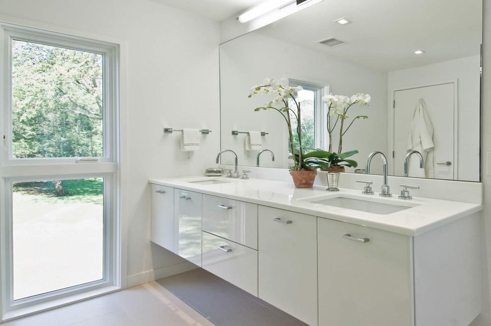 Immagine di una stanza da bagno minimalista con lavabo sottopiano, ante lisce, ante bianche e top bianco