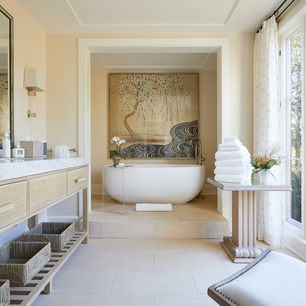 Réalisation d'une salle de bain principale champêtre en bois clair avec une baignoire indépendante, un mur beige, un sol beige, un plan de toilette blanc et un placard à porte plane.