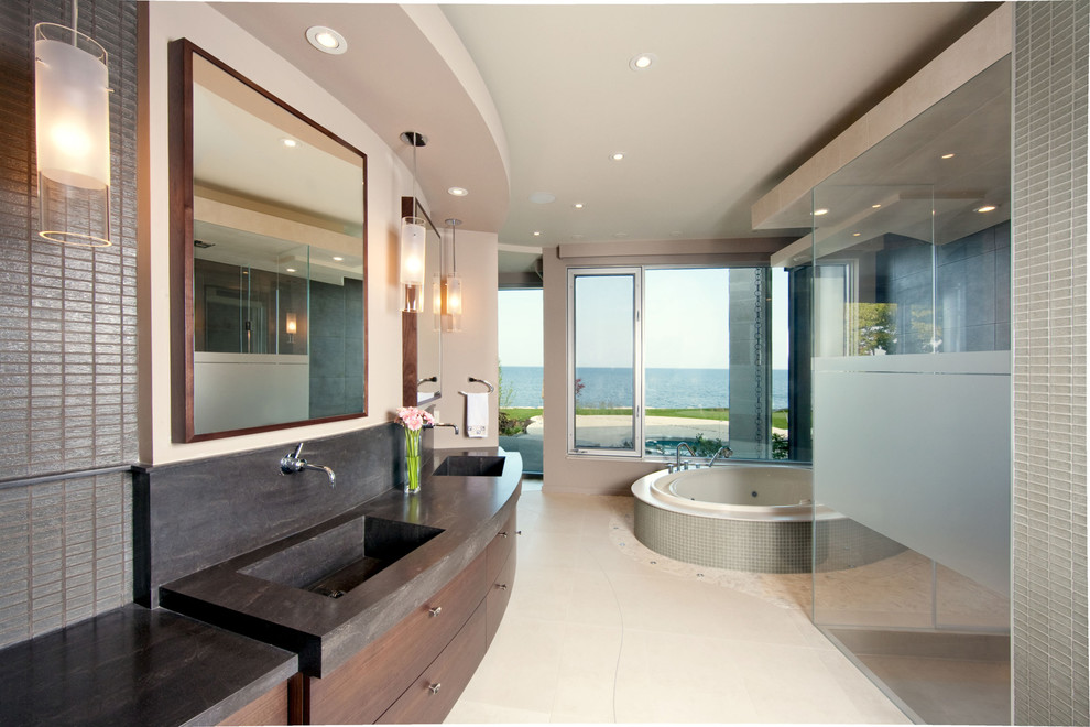 Foto de cuarto de baño contemporáneo con lavabo integrado, armarios con paneles lisos, puertas de armario de madera en tonos medios, ducha esquinera, baldosas y/o azulejos grises y jacuzzi