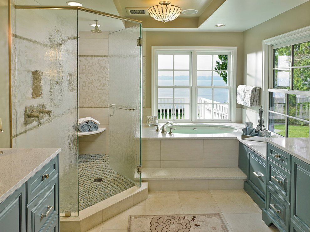 This is an example of a medium sized traditional ensuite bathroom in Seattle with raised-panel cabinets, blue cabinets, an alcove bath, a corner shower, beige walls, travertine flooring, solid surface worktops, beige floors, a submerged sink and a hinged door.