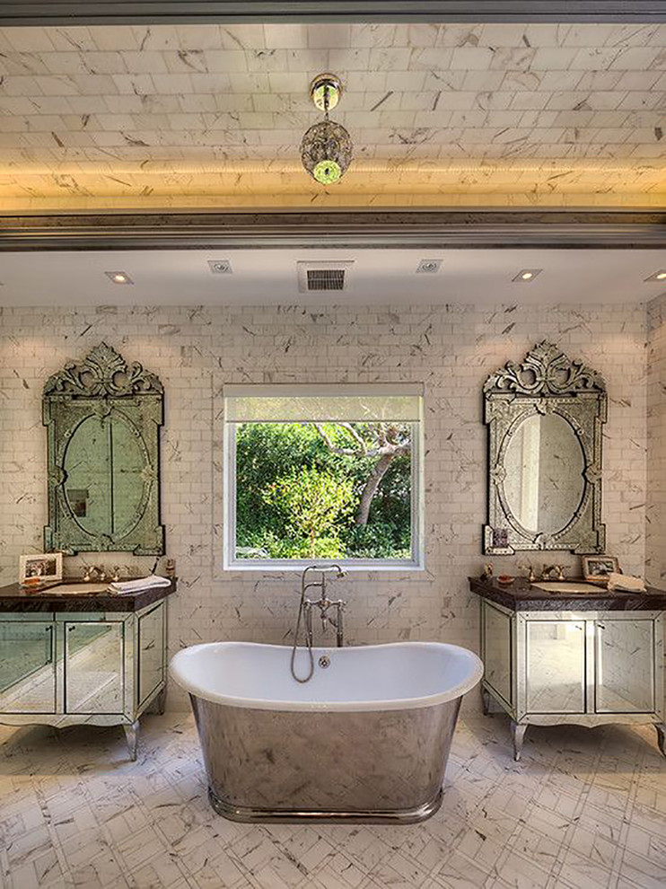 Expansive midcentury bathroom in San Diego with a built-in sink, a freestanding bath, freestanding cabinets, white tiles, stone tiles, white walls and marble flooring.