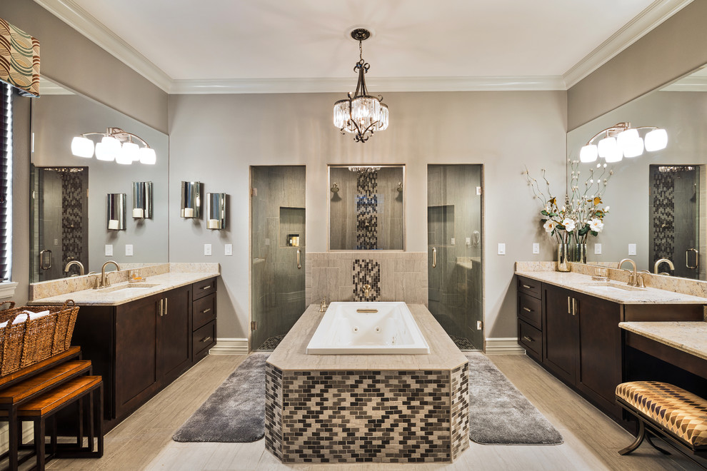 Mediterranean ensuite bathroom in Orlando with shaker cabinets, dark wood cabinets, a built-in bath, a double shower, grey tiles, grey walls, a submerged sink, grey floors and beige worktops.