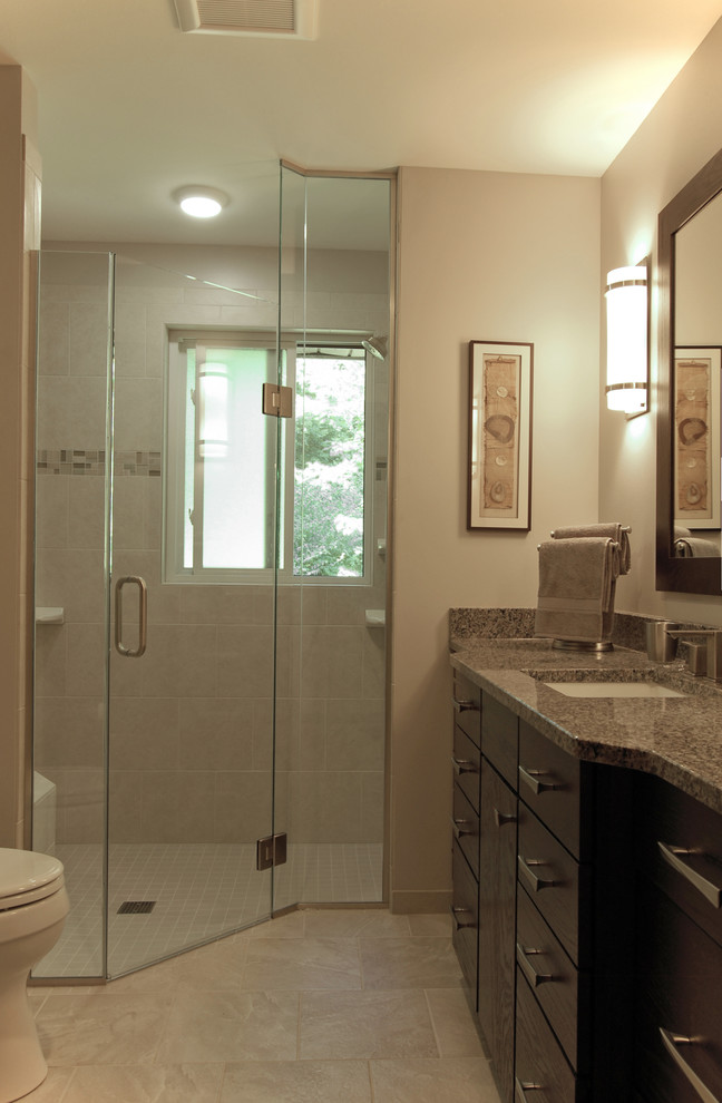 This is an example of a medium sized contemporary ensuite bathroom in Milwaukee with a submerged sink, flat-panel cabinets, dark wood cabinets, engineered stone worktops, a built-in shower, a two-piece toilet, grey tiles, porcelain tiles, beige walls and porcelain flooring.