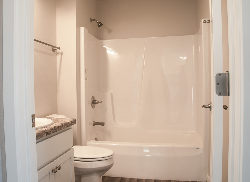 Foto på ett litet vintage flerfärgad badrum med dusch, med skåp i shakerstil, vita skåp, ett hörnbadkar, en dusch/badkar-kombination, en toalettstol med hel cisternkåpa, beige väggar, mörkt trägolv, ett nedsänkt handfat, laminatbänkskiva, brunt golv och dusch med duschdraperi