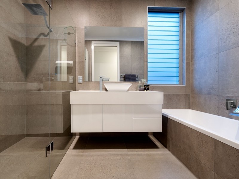 Inspiration for a medium sized contemporary ensuite bathroom in Brisbane with flat-panel cabinets, white cabinets, an alcove bath, grey tiles, cement tiles, grey walls, cement flooring, a vessel sink and grey floors.