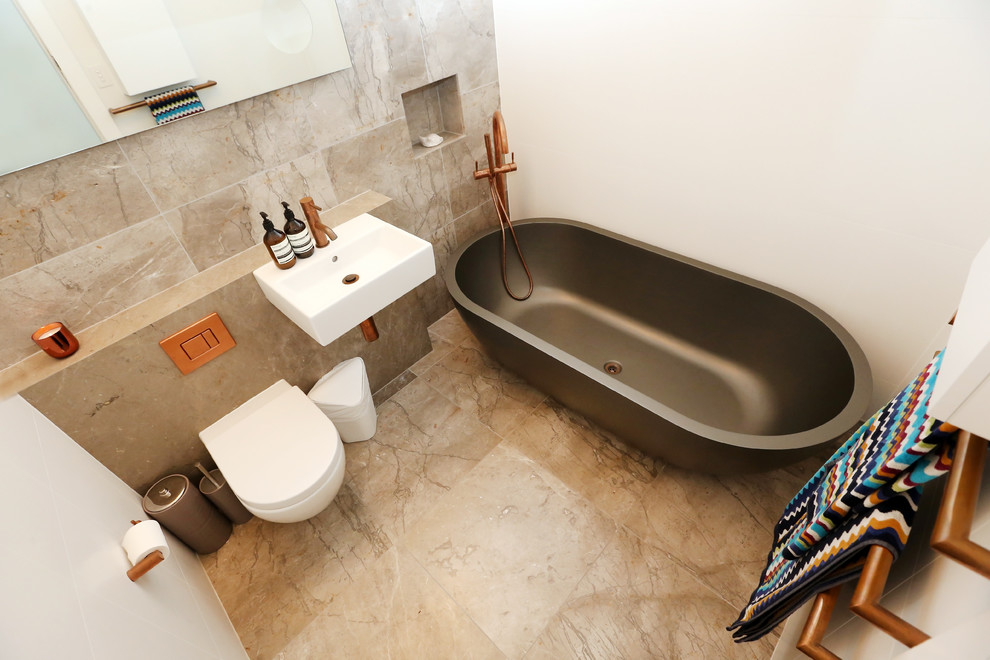 Idéer för ett litet modernt badrum, med grå kakel, stenkakel, marmorgolv, marmorbänkskiva, luckor med upphöjd panel, ett fristående badkar, en vägghängd toalettstol, vita väggar och ett väggmonterat handfat