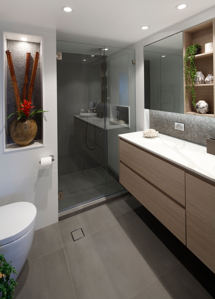 Inspiration för mellanstora moderna vitt badrum med dusch, med släta luckor, skåp i ljust trä, en öppen dusch, en vägghängd toalettstol, grå kakel, porslinskakel, grå väggar, klinkergolv i porslin, ett nedsänkt handfat, bänkskiva i kvarts, grått golv och med dusch som är öppen