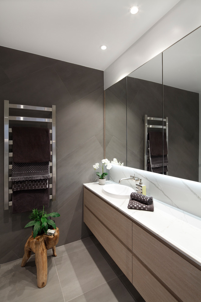 Mid-sized minimalist master gray tile and porcelain tile porcelain tile and gray floor bathroom photo in Sydney with flat-panel cabinets, light wood cabinets, a wall-mount toilet, gray walls, a drop-in sink, quartz countertops and white countertops