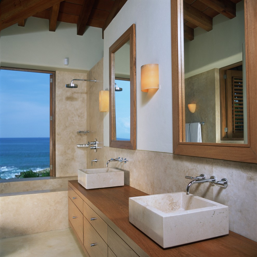 Inspiration for a large tropical master beige tile bathroom remodel in Other with furniture-like cabinets, medium tone wood cabinets, wood countertops and white walls
