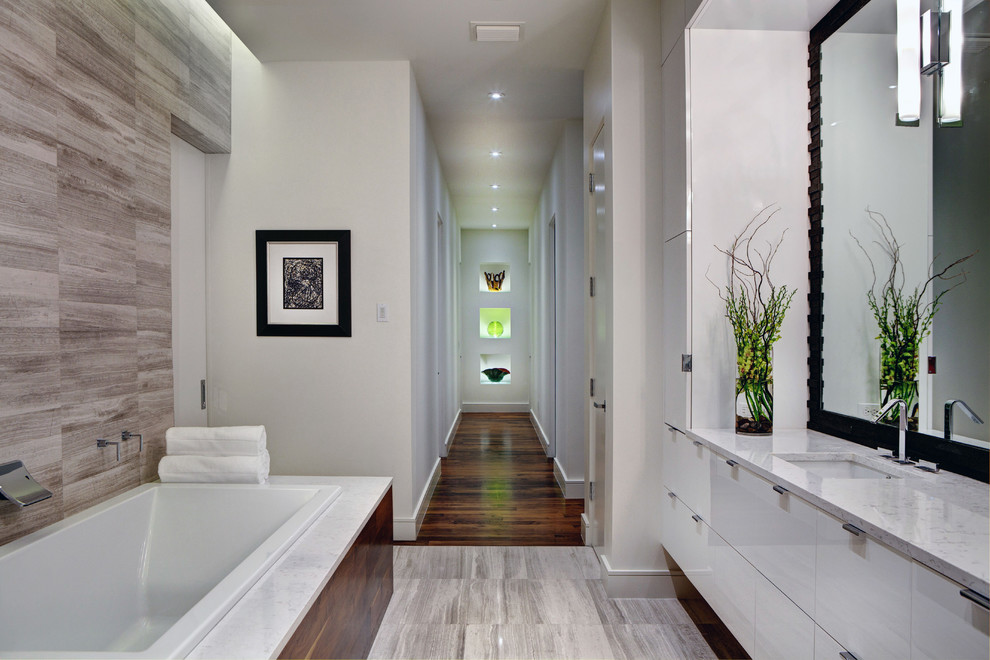 Exemple d'une grande salle de bain principale moderne avec un mur blanc, parquet foncé, un lavabo encastré, un sol marron, un placard à porte plane, des portes de placard blanches, une baignoire posée et un plan de toilette en quartz.