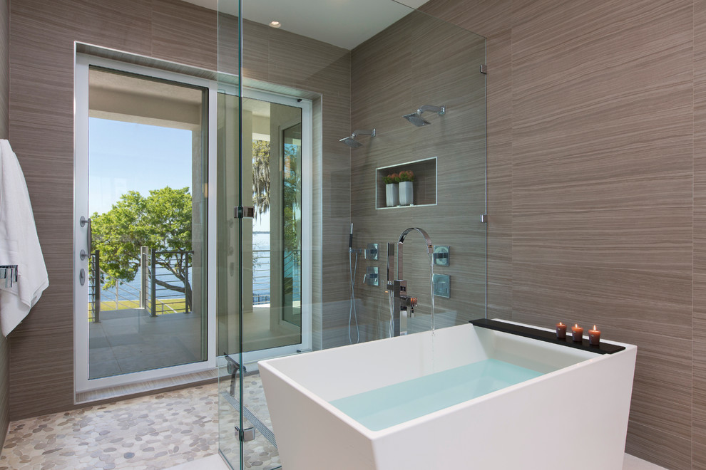 Modelo de cuarto de baño principal moderno de tamaño medio con bañera exenta, ducha abierta, paredes beige y suelo de travertino