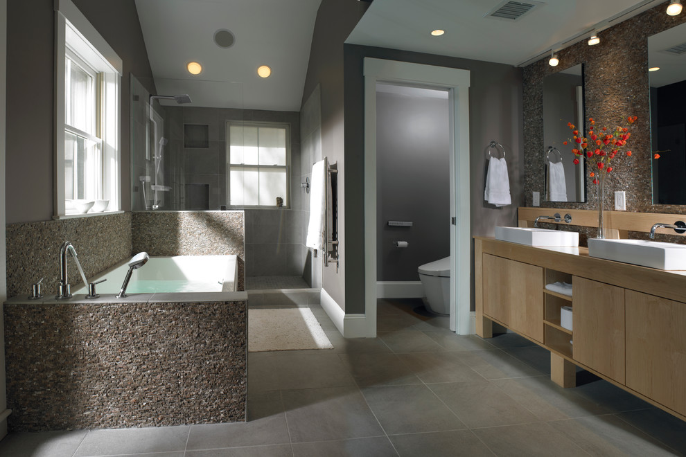 Idéer för att renovera ett stort funkis beige beige en-suite badrum, med ett fristående handfat, släta luckor, ett badkar i en alkov, en dusch i en alkov, grå kakel, skåp i ljust trä, cementkakel, grå väggar och träbänkskiva