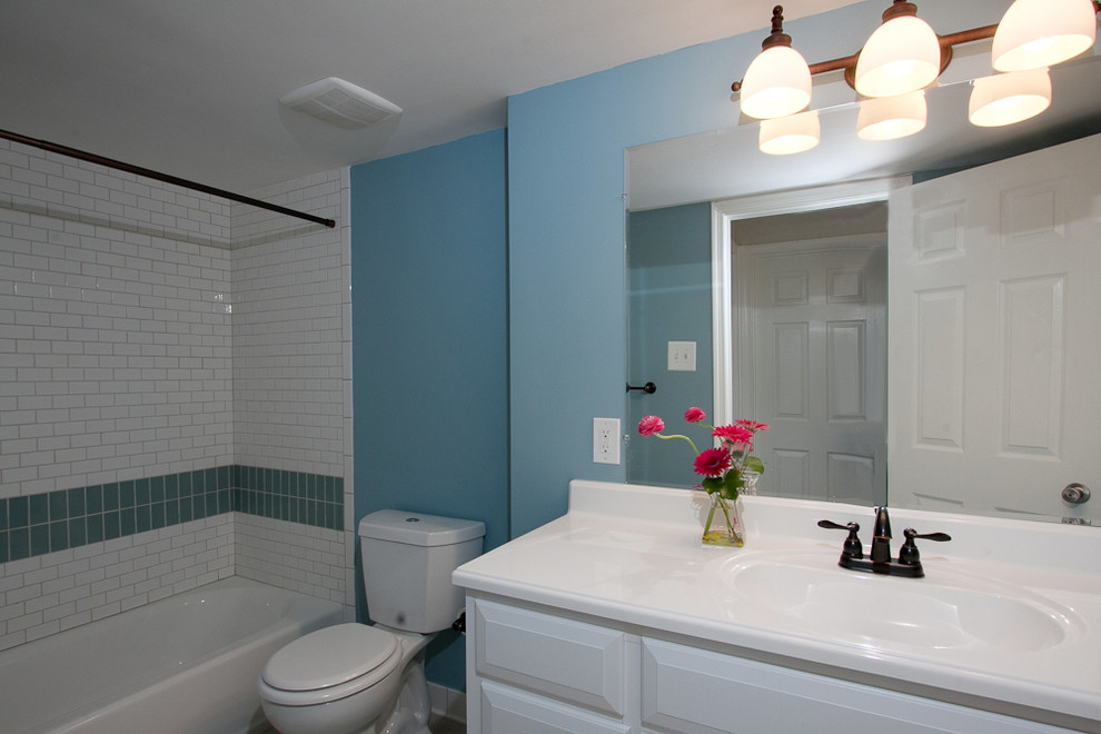 Идея дизайна: ванная комната среднего размера в стиле неоклассика (современная классика) с фасадами с выступающей филенкой, белыми фасадами, ванной в нише, душем над ванной, зеленой плиткой, белой плиткой, синими стенами, монолитной раковиной и шторкой для ванной