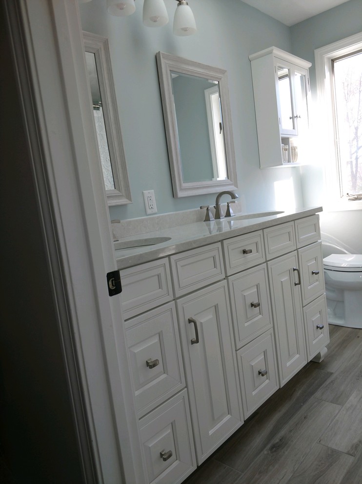 Пример оригинального дизайна: ванная комната среднего размера в классическом стиле с фасадами с выступающей филенкой, раздельным унитазом, темным паркетным полом, душевой кабиной, коричневым полом, белыми фасадами, ванной в нише, душем над ванной, серыми стенами, врезной раковиной, шторкой для ванной и белой столешницей