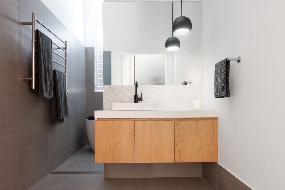 Idée de décoration pour une salle de bain design en bois brun avec un placard à porte plane, un mur blanc, une vasque, un sol gris et un plan de toilette blanc.