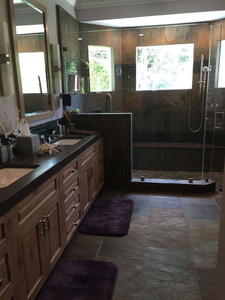 Photo of a contemporary bathroom in San Francisco with a submerged sink, raised-panel cabinets, light wood cabinets, a corner shower, stone tiles, grey walls and slate flooring.