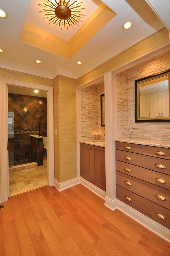 This is an example of a large classic ensuite bathroom in Other with shaker cabinets, medium wood cabinets, an alcove shower, beige tiles, stone slabs, beige walls, medium hardwood flooring, a submerged sink and granite worktops.