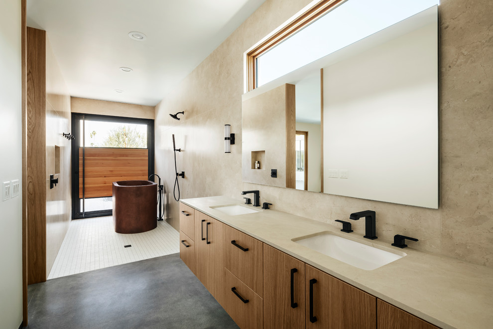 Idéer för amerikanska beige en-suite badrum, med släta luckor, ett fristående badkar, beige kakel, marmorkakel, betonggolv, ett undermonterad handfat, marmorbänkskiva, med dusch som är öppen, våtrum, beige väggar, grått golv och skåp i ljust trä