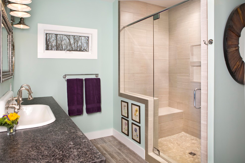 Cette image montre une salle de bain rustique en bois clair de taille moyenne avec un placard à porte plane, un mur bleu, un sol en vinyl, un lavabo posé, un plan de toilette en stéatite, un sol gris et une cabine de douche à porte battante.