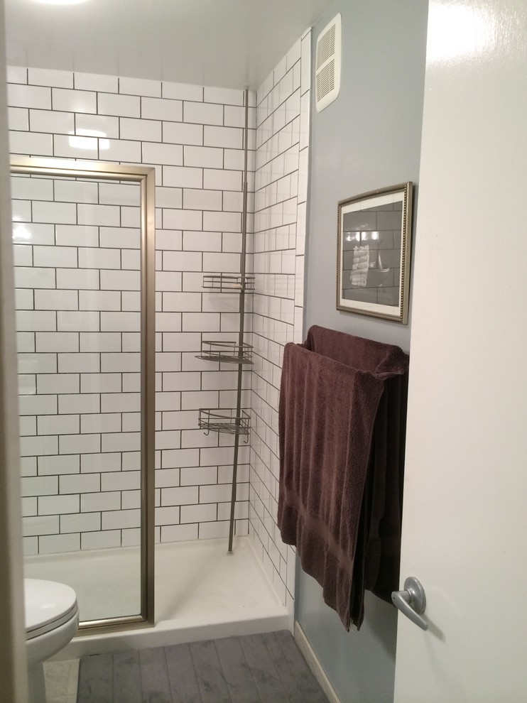 Exempel på ett mellanstort klassiskt svart svart badrum med dusch, med luckor med upphöjd panel, vita skåp, en dusch i en alkov, en toalettstol med separat cisternkåpa, vit kakel, tunnelbanekakel, grå väggar, klinkergolv i porslin, ett undermonterad handfat, bänkskiva i akrylsten, grått golv och dusch med gångjärnsdörr