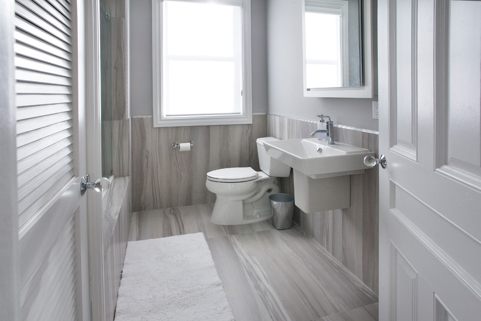Modern inredning av ett litet badrum med dusch, med en dusch/badkar-kombination, en toalettstol med hel cisternkåpa, grå väggar och ett integrerad handfat