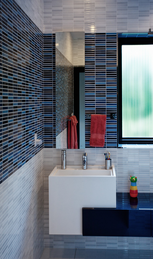 Пример оригинального дизайна: детская ванная комната в современном стиле с подвесной раковиной, синей плиткой и удлиненной плиткой