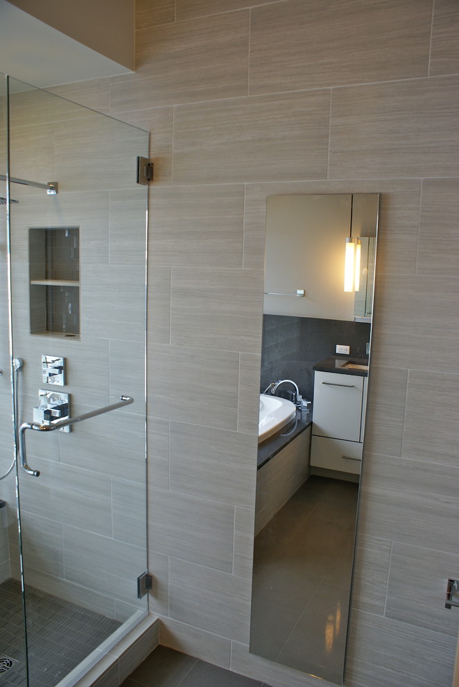 Bild på ett funkis badrum, med ett undermonterad handfat, släta luckor, vita skåp, bänkskiva i kvarts, ett platsbyggt badkar, en toalettstol med separat cisternkåpa, grå kakel och porslinskakel