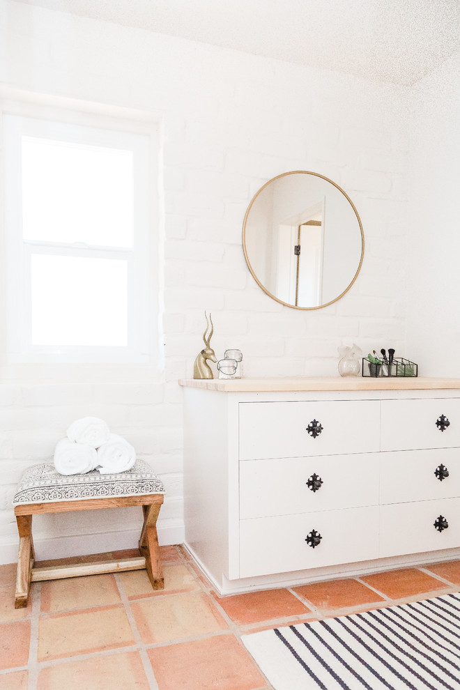 Cette photo montre une salle de bain sud-ouest américain avec des portes de placard blanches, un mur blanc, tomettes au sol, un sol orange et un placard à porte plane.