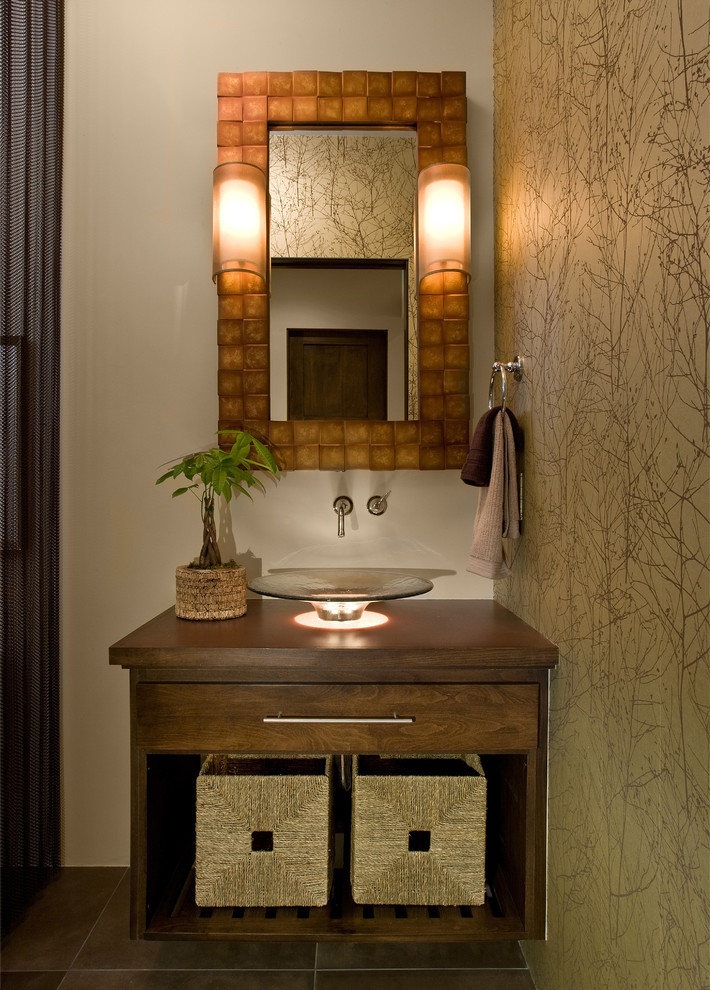 Cette image montre une salle de bain chalet avec une vasque, des portes de placard marrons, un plan de toilette en bois, WC à poser, un carrelage marron, des carreaux de céramique, un mur marron, un sol en carrelage de céramique et un placard à porte plane.