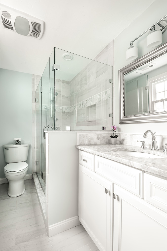 Small transitional master porcelain tile porcelain tile corner shower photo in Boston with recessed-panel cabinets, white cabinets, blue walls, an undermount sink, marble countertops and a hinged shower door