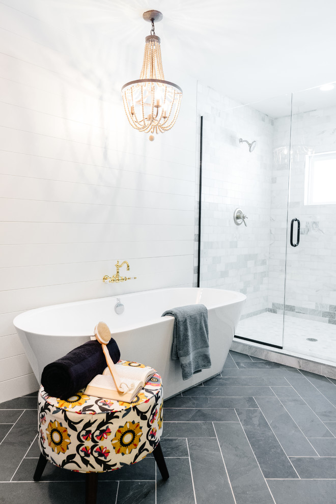 This is an example of a large farmhouse ensuite bathroom in Phoenix with a freestanding bath, a walk-in shower, white tiles, marble tiles, slate flooring, black floors and a hinged door.