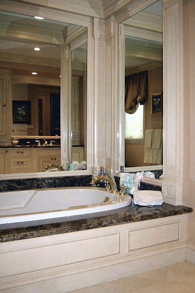 Large elegant master limestone floor and beige floor drop-in bathtub photo in Boston with recessed-panel cabinets, beige cabinets, a one-piece toilet, beige walls, an undermount sink and marble countertops
