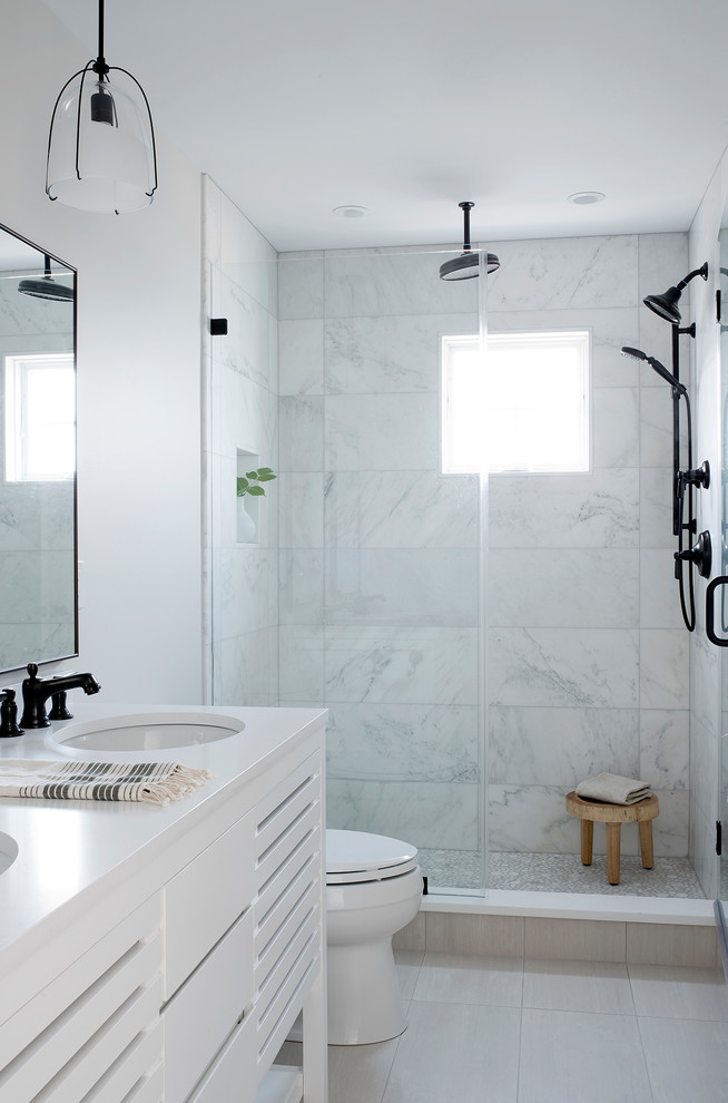 This is an example of a beach style shower room bathroom in Portland Maine with shaker cabinets, white cabinets, a corner shower, white tiles, metro tiles, white walls, a submerged sink, grey floors and grey worktops.