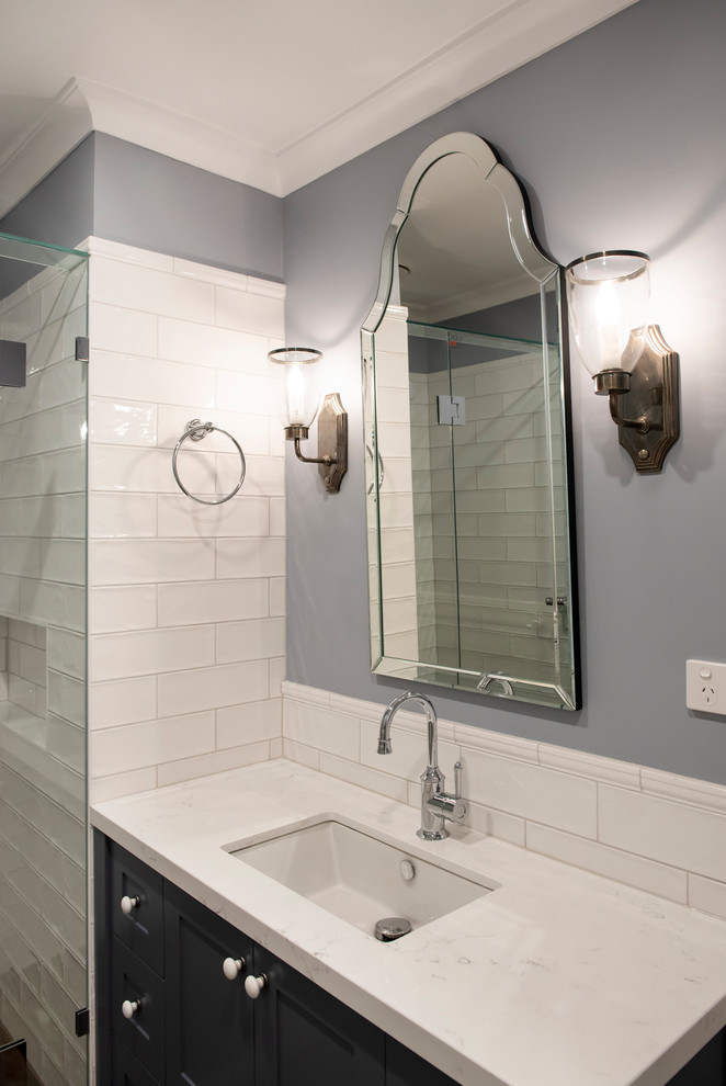 На фото: ванная комната среднего размера в классическом стиле с фасадами в стиле шейкер, серыми фасадами, душем в нише, унитазом-моноблоком, белой плиткой, синими стенами, полом из керамогранита, душевой кабиной, врезной раковиной, столешницей из искусственного кварца, коричневым полом, душем с распашными дверями, белой столешницей и плиткой кабанчик с