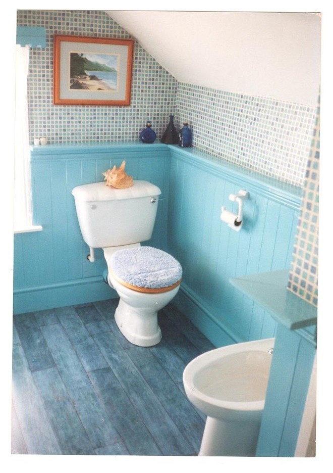 This is an example of a small rural family bathroom in Cheshire with raised-panel cabinets, blue cabinets, a built-in bath, a shower/bath combination, white tiles, ceramic tiles, blue walls, laminate floors and a pedestal sink.