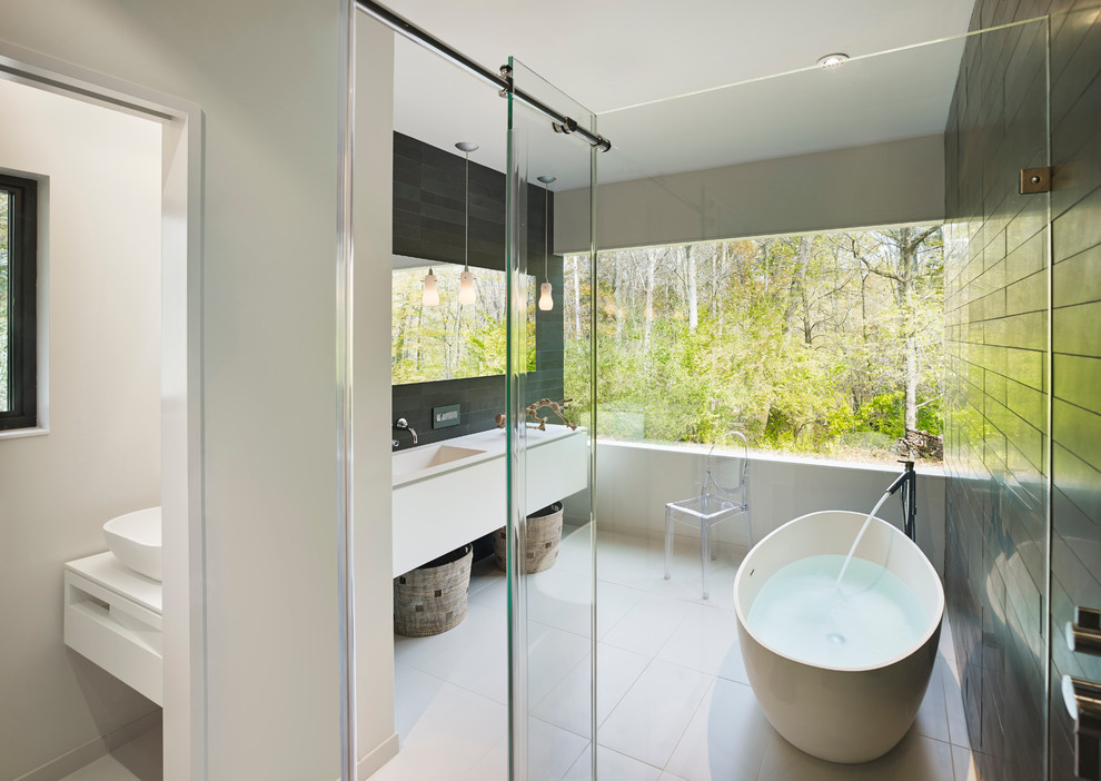 Exempel på ett modernt en-suite badrum, med släta luckor, vita skåp, bänkskiva i akrylsten, svart kakel, stenkakel, ett fristående badkar, en hörndusch, ett integrerad handfat, vita väggar och klinkergolv i porslin