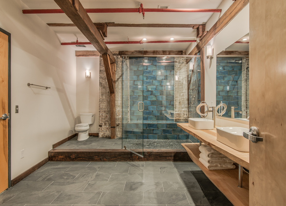 This is an example of a large urban ensuite bathroom in Nashville with a vessel sink, open cabinets, light wood cabinets, wooden worktops, a built-in shower, blue tiles, ceramic tiles, white walls and slate flooring.