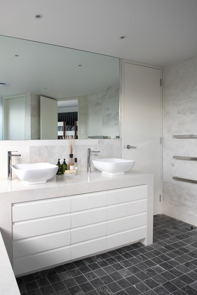 На фото: ванная комната в современном стиле с настольной раковиной, белыми фасадами и серой плиткой с