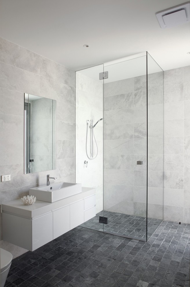 Ejemplo de cuarto de baño gris y blanco actual con armarios con paneles lisos, puertas de armario blancas, ducha a ras de suelo, baldosas y/o azulejos grises, paredes grises y suelo gris