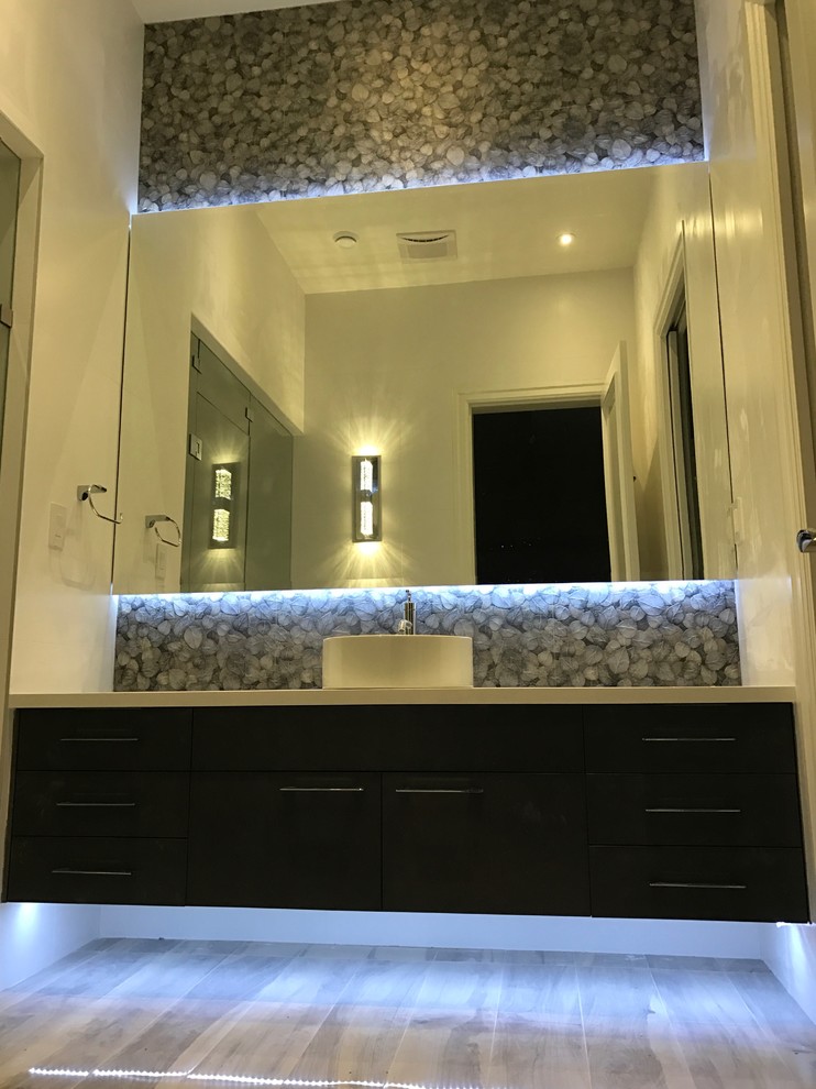 Пример оригинального дизайна: ванная комната среднего размера в современном стиле с плоскими фасадами, черными фасадами, душем в нише, душевой кабиной, раковиной с несколькими смесителями, душем с распашными дверями, серой плиткой, керамогранитной плиткой, белыми стенами, светлым паркетным полом, столешницей из искусственного камня и коричневым полом