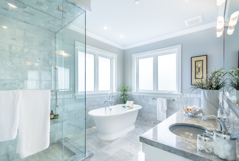 バンクーバーにあるトランジショナルスタイルのおしゃれな浴室 (アンダーカウンター洗面器、置き型浴槽、グレーのタイル、グレーの壁) の写真